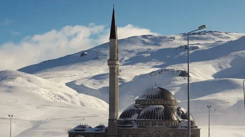 Mosque against the backdrop of snow-capped mountains and blue sky Stock Footage 124018467