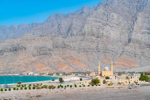 Mosque with two minarets and a small fort with ocean and tall mountain cliffs in Stock Photos