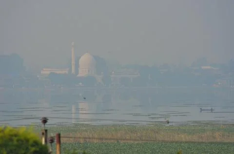 A mosque of white marble on the far side of a lake covered in morning mist Stock Photos