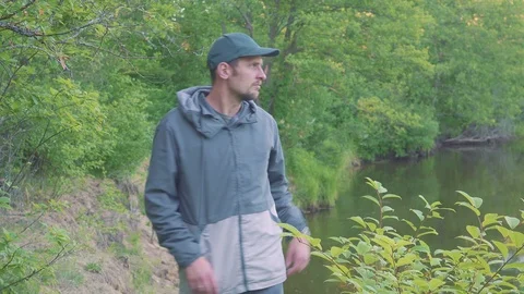 Mosquitoes and beetles attack a young man near the river. A man is waving his Video stock 90925322