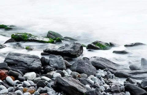 Moss-Covered Rocks Beside Flowing Water in Serene Nature Scene Stock Photos