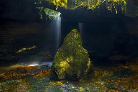 Mossy stone with cave in the background with waterfall Stock Illustration