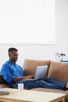 The most comfortable way to work. A handsome young woman sitting on a sofa with Stock Photos