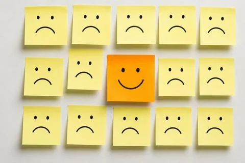 Most of the notes are yellow and feature a hand-drawn sad face. Stock Photos