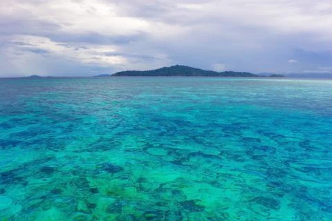 Mostly cloudy day with blue green ocean which we can see corals on sea ground. Stock Photos