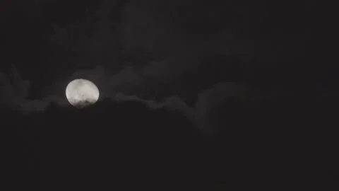 Mostly full glowing yellow moon with clouds being blown by winds at night. Stock Footage 163002823