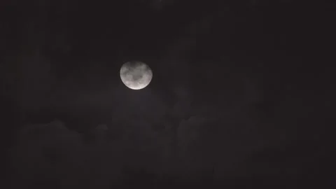 Mostly full glowing yellow moon with clouds being blown by winds at night. Stock Footage 163003061
