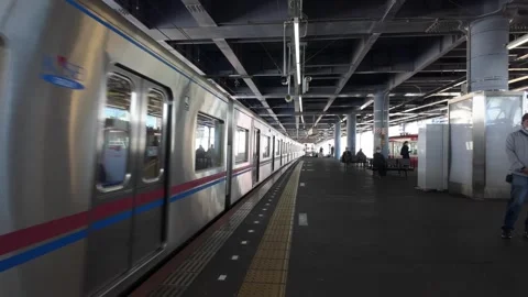 A mostly steady platform view shows a passenger train approaching and passing Stock Footage 346514820