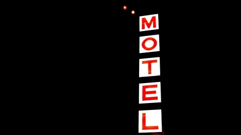 A motel sign brightly lit in the night sky. Stock Footage