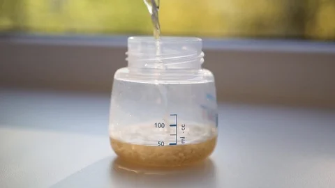 Mother adding water in children's bottle, bottle standing, slowmotion Stock Footage 89176255