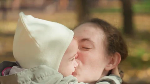 Mother affectionately presses her infant in open air. Mother lovingly shares 動画素材 334626478