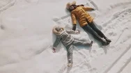 A Mother And Baby Are Making Angels On The Snow. Family Have Fun With Copyspace Stock Footage