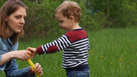 Mother and baby blowing soap bubble outdoors Stock Footage