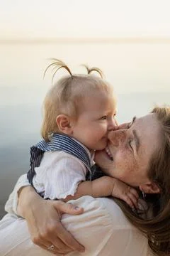 Mother and baby sharing a tender moment outdoors with a soft natural backgrou Stock Photos