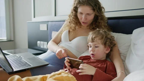 Mother and child bonding while enjoying a mobile game in a cozy hotel room Video stock 296513768