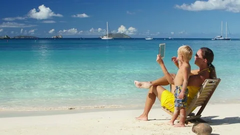 Mother and child browsing on tablet on tropical beach Stock Footage 69784119