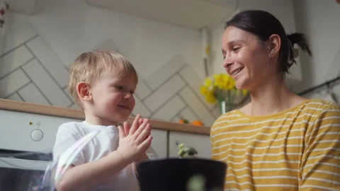 Mother and child clapping their hands after planting seedlings in pots Stock Footage 331438977