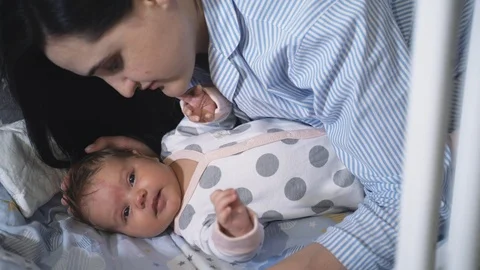 Mother and child lying in the crib, the mother kisses the baby. 動画素材 118617841