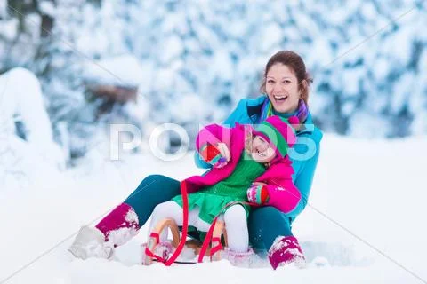 Mother and child sledding in a snowy park Stock Photos