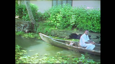 Mother and child watch a row boat pass in Kerala Backwaters - India Stock Footage 240055152
