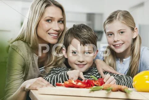 Mother and children cutting vegetables in kitchen Stock Photos