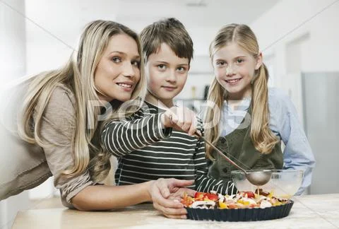 Mother and children with pizza in kitchen Stock Photos