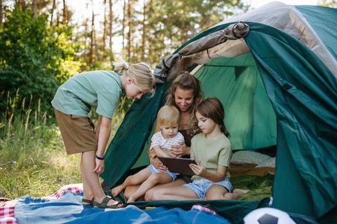 Mother and children using tablet together during family camping trip. Stock Photos
