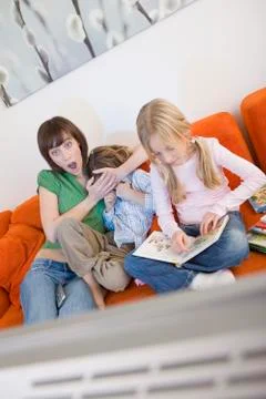 Mother and children watching television together Stock Photos