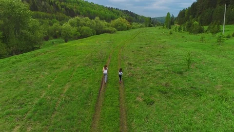 Mother and daughter are running together on a green meadow. Stock Footage