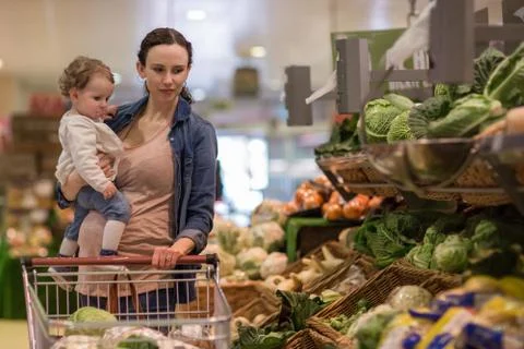 Mother and daughter buying vegetables in grocery store Stock Photos