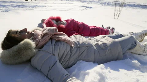 Mother and daughter chilling on the snow on a sunny winter day slow motion Video stock 59793739