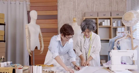 Mother and daughter collaborating at worktable arranging fabric boutique fashion Stock-Footage 335271156