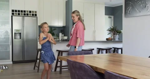 Mother and daughter dancing in kitchen girl dancing mother reaching to high-five Stock Footage 343516831