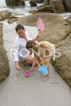 Mother and daughter drawing on sand. Stock Photos