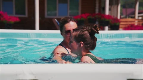 Mother and daughter float in pool, sharing happy glances Vídeo Stock 333512112