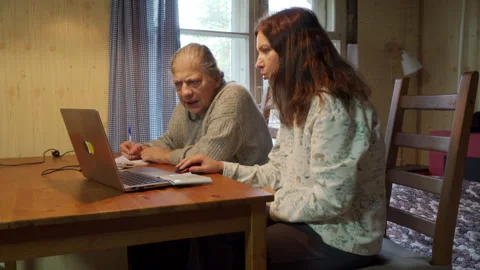 Mother and Daughter Focus on Computer Work and Notes at Rustic Table. Stock Footage 321154381