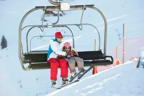 Mother And Daughter Getting Off chair Lift On Ski Holiday In Mountains Stock Photos