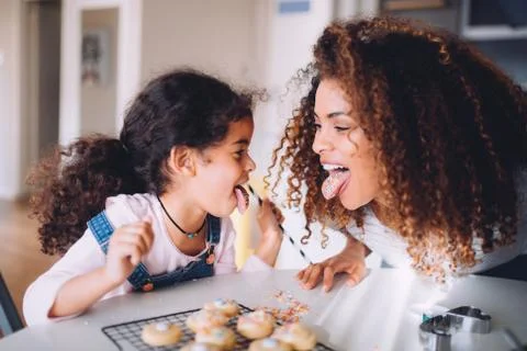 Mother and daughter having fun eating cookies together Stock Photos