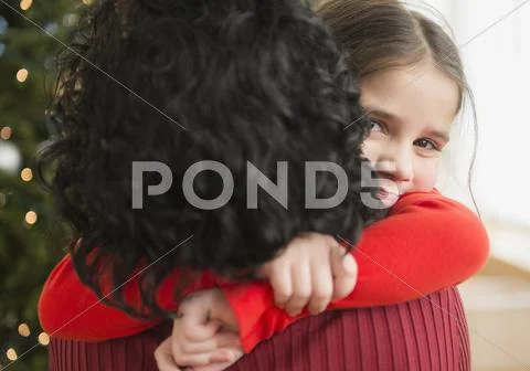 Mother and daughter hugging by Christmas tree Stock Photos