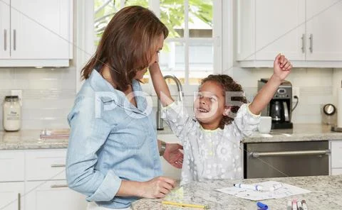 Mother And Daughter At Kitchen Counter Drawing Pictures, Arms Raised