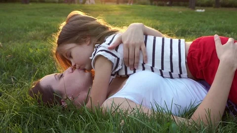 mom son tongue kissing Mother and daughter lying on grass. Kiss | Stock Video | Pond5