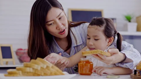 Mother and daughter make breakfast bread with fruit jam in kitchen at home Stockbeeldmateriaal 181556264