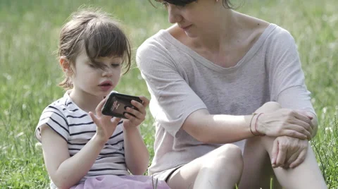 Mother and daughter playing with smartphone at the park. 스톡 동영상 50856470