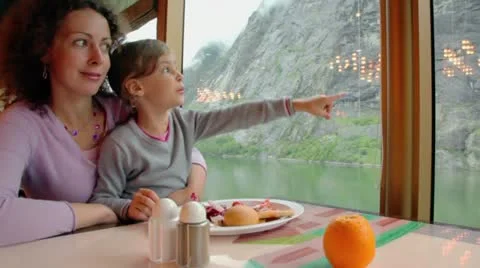 Mother and daughter sit at table with food and watch mountain Stock Footage