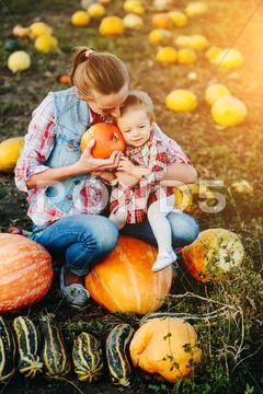 Mother and daughter sitting on pumpkins Stock Photos