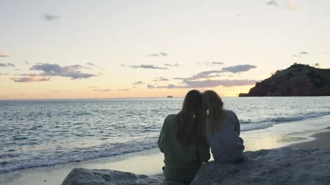 A mother and daughter sitting on rocks on the seashore admiring the view. Stock Footage 321287953