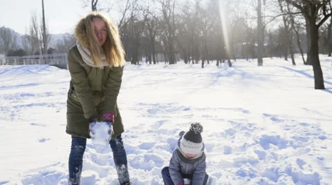 Mother and daughter trowing up some snow in the park slow motion Video stock 59795931