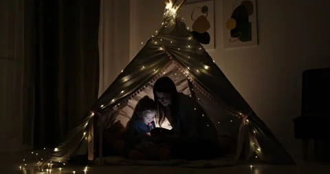 Mother and daughter using device in tent Stock Footage 164174074