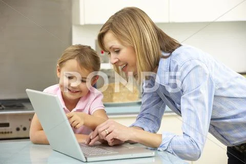 Mother and daughter using laptop in domestic kitchen Stock-Fotos
