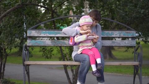 Mother and daughter using phone on outside a cool evening Stock Footage 79772412